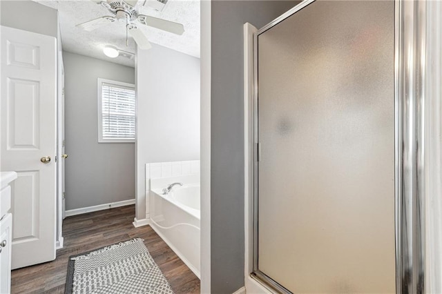 bathroom with a garden tub, a shower stall, a textured ceiling, and wood finished floors