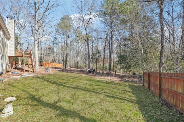 view of yard featuring a deck, stairway, and fence