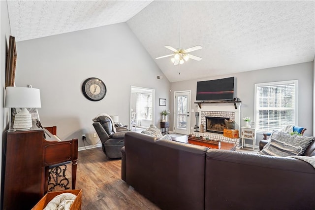 living area with ceiling fan, a healthy amount of sunlight, a fireplace, and wood finished floors