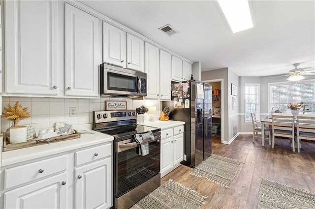 kitchen featuring visible vents, light wood-style flooring, backsplash, appliances with stainless steel finishes, and white cabinets