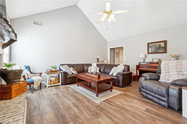 living area featuring high vaulted ceiling, a ceiling fan, visible vents, and wood finished floors