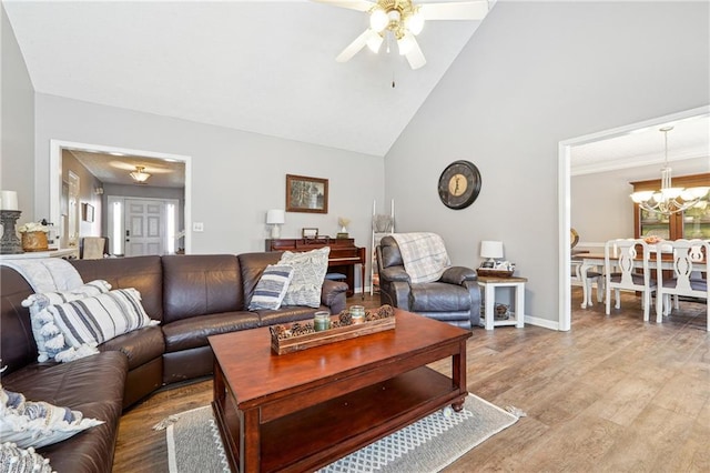 living room featuring high vaulted ceiling, light wood-type flooring, baseboards, and ceiling fan with notable chandelier