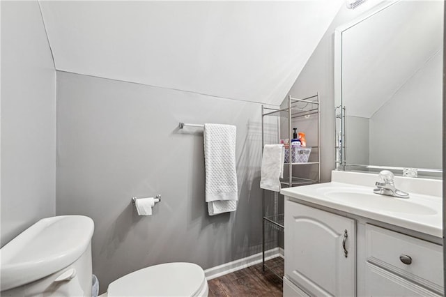 bathroom with toilet, wood finished floors, vanity, baseboards, and vaulted ceiling