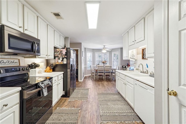 kitchen with visible vents, decorative backsplash, white cabinets, stainless steel appliances, and a sink