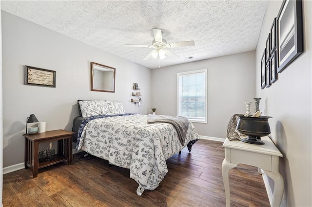 bedroom with visible vents, dark wood-type flooring, ceiling fan, a textured ceiling, and baseboards