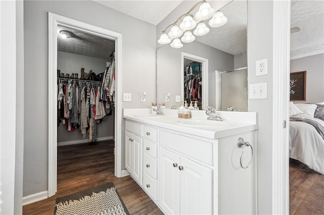 ensuite bathroom with a sink, double vanity, connected bathroom, and wood finished floors