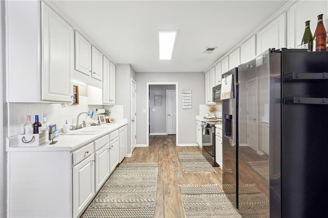 kitchen featuring visible vents, white cabinets, stainless steel appliances, light countertops, and a sink