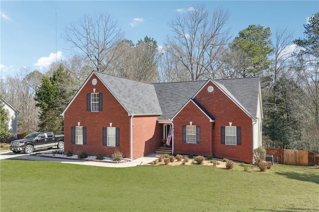 view of front facade with brick siding, fence, and a front yard