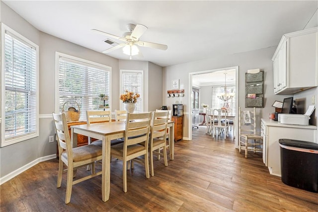 dining space with ceiling fan with notable chandelier, dark wood-style flooring, visible vents, and baseboards