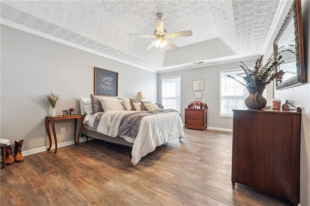 bedroom featuring crown molding, a raised ceiling, a textured ceiling, wood finished floors, and baseboards