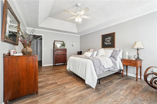 bedroom featuring crown molding, a textured ceiling, a tray ceiling, and wood finished floors