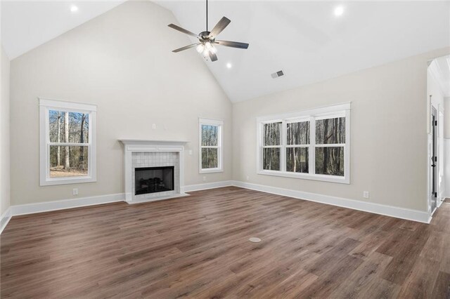 473 Nugget Rd, Carrollton, GA 30117 - unfurnished living room with dark wood-style flooring, visible vents, high vaulted ceiling, a tile fireplace, and baseboards