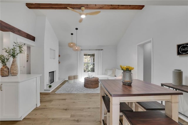 dining space with high vaulted ceiling, beam ceiling, and light hardwood / wood-style flooring