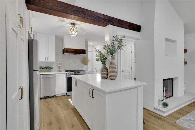 kitchen featuring light hardwood / wood-style flooring, premium range hood, white cabinetry, stainless steel appliances, and a center island