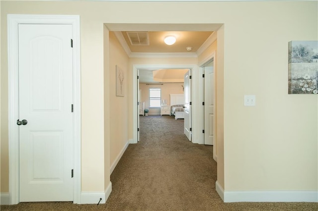 hallway with baseboards, carpet, visible vents, and ornamental molding