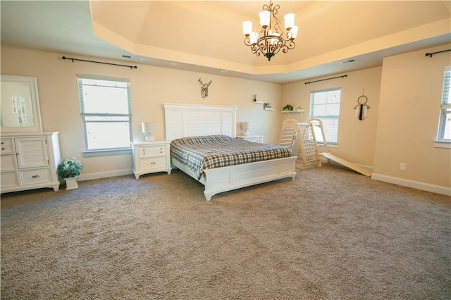 unfurnished bedroom with visible vents, a notable chandelier, a tray ceiling, carpet floors, and baseboards