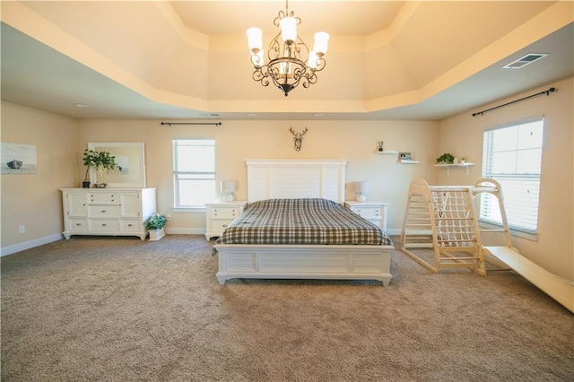 carpeted bedroom featuring multiple windows, a raised ceiling, and baseboards