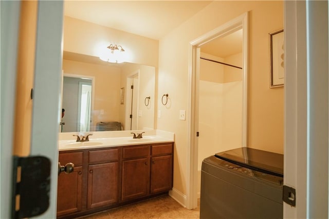 bathroom with tile patterned flooring, double vanity, a shower, and a sink