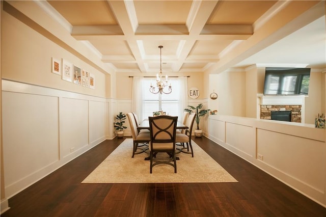 dining room with beamed ceiling, coffered ceiling, dark wood-type flooring, a decorative wall, and a chandelier