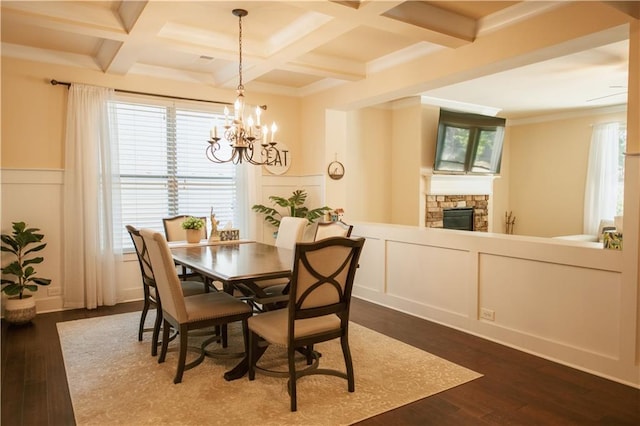 dining area with dark wood-style floors, coffered ceiling, an inviting chandelier, beam ceiling, and a decorative wall