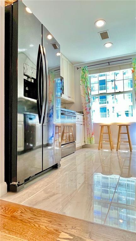 kitchen featuring stainless steel fridge with ice dispenser, visible vents, white cabinets, recessed lighting, and range
