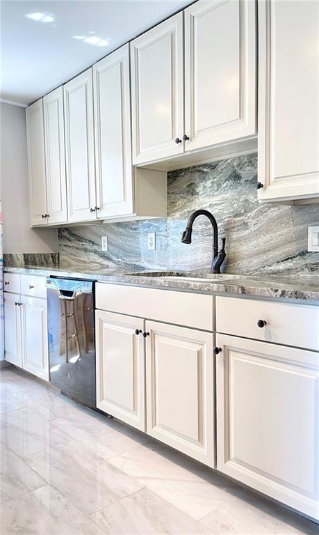 kitchen featuring light stone counters, white cabinets, decorative backsplash, dishwasher, and a sink