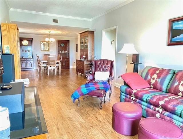 living room featuring a chandelier, visible vents, ornamental molding, and wood finished floors