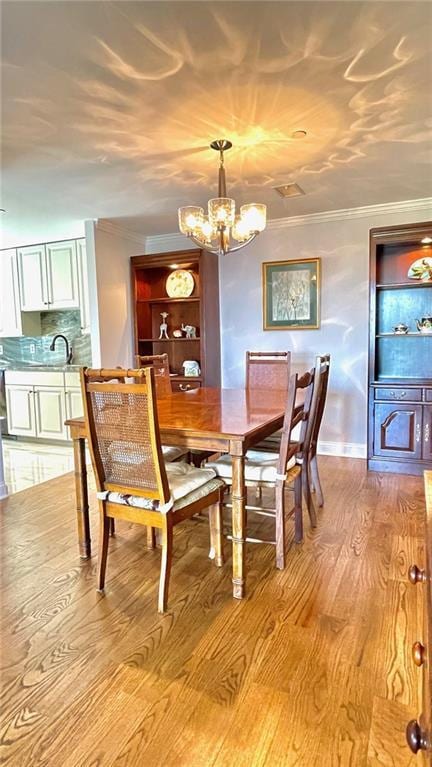 dining area featuring crown molding, a chandelier, and light wood-style floors