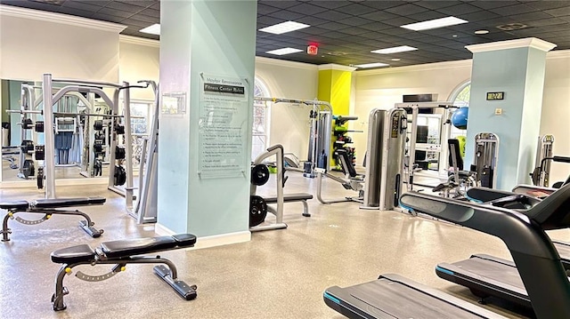 gym with a paneled ceiling, baseboards, and ornamental molding