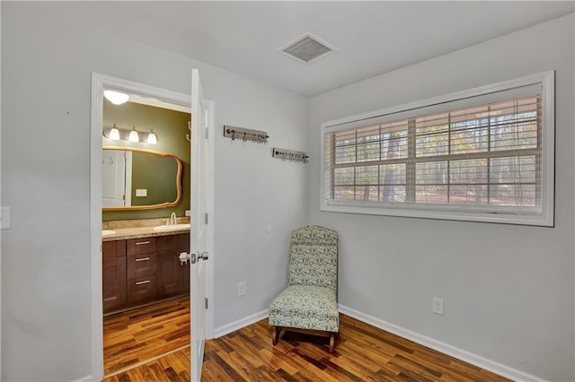 living area featuring visible vents, baseboards, and wood finished floors