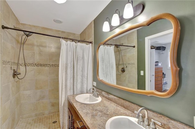 full bath with double vanity, a tile shower, and a sink