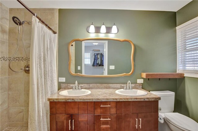 full bath with a wealth of natural light, a tile shower, and a sink