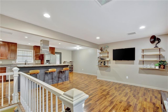 living area with light wood-style floors, recessed lighting, visible vents, and baseboards