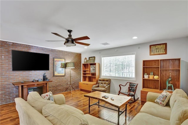 living room with recessed lighting, visible vents, brick wall, and wood finished floors