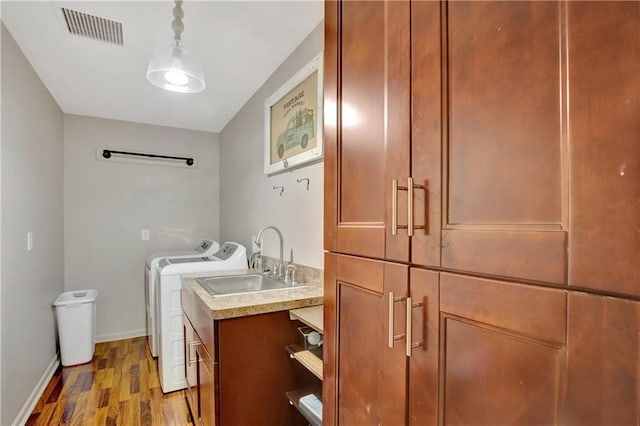 washroom featuring cabinet space, visible vents, dark wood-type flooring, a sink, and separate washer and dryer