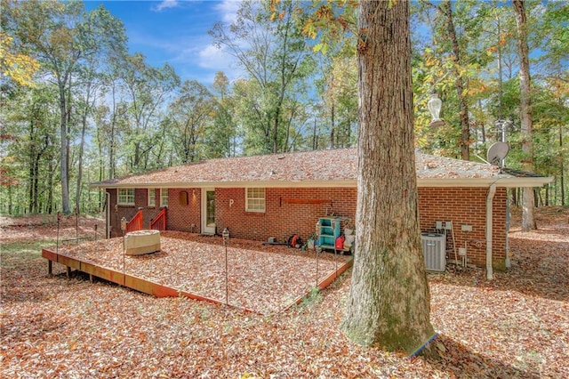 rear view of house with central AC unit and brick siding