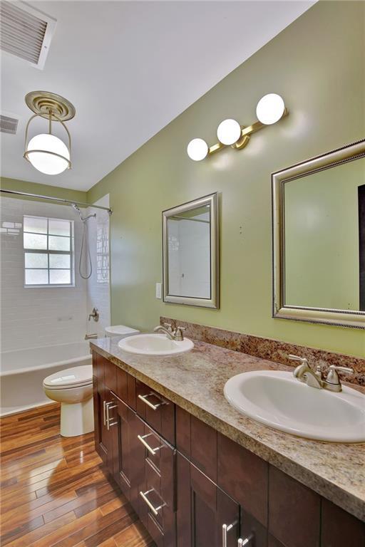 bathroom with wood finished floors, shower / washtub combination, a sink, and visible vents