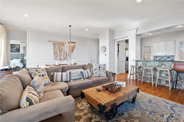 living room with hardwood / wood-style floors, an inviting chandelier, and ornamental molding