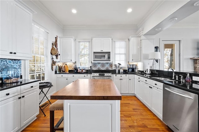 kitchen featuring a center island, sink, light hardwood / wood-style flooring, white cabinetry, and stainless steel appliances