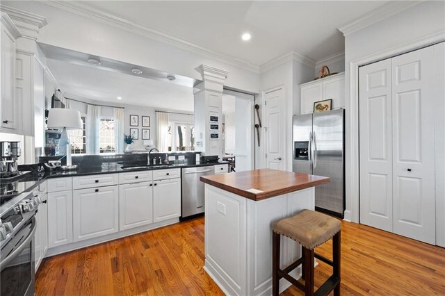 kitchen featuring a kitchen bar, light wood-type flooring, white cabinetry, and appliances with stainless steel finishes