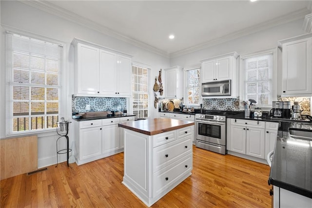 kitchen featuring white cabinets, appliances with stainless steel finishes, and plenty of natural light