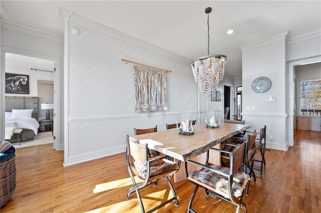 dining space with light hardwood / wood-style floors, ornamental molding, and a chandelier