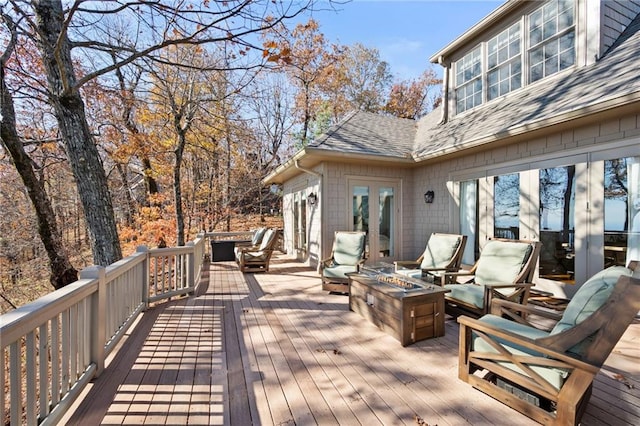 wooden terrace with an outdoor fire pit and french doors