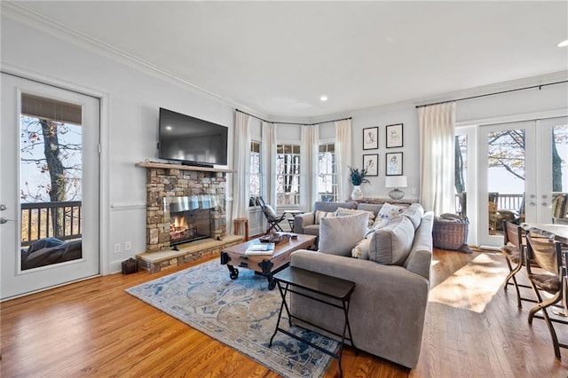 living room with a stone fireplace, plenty of natural light, hardwood / wood-style floors, and ornamental molding