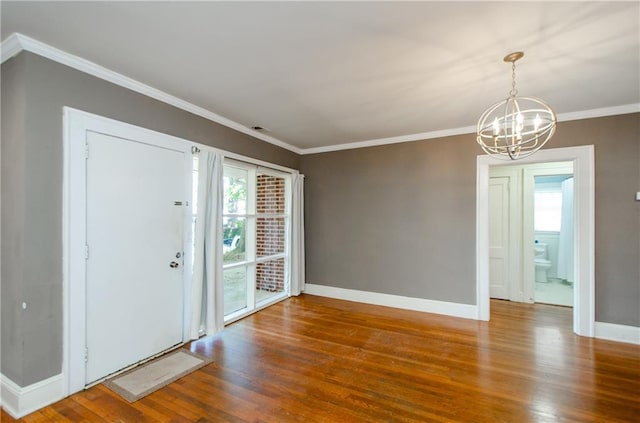 foyer with crown molding, wood-type flooring, and an inviting chandelier