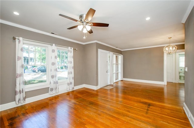 spare room with hardwood / wood-style floors, crown molding, and ceiling fan with notable chandelier