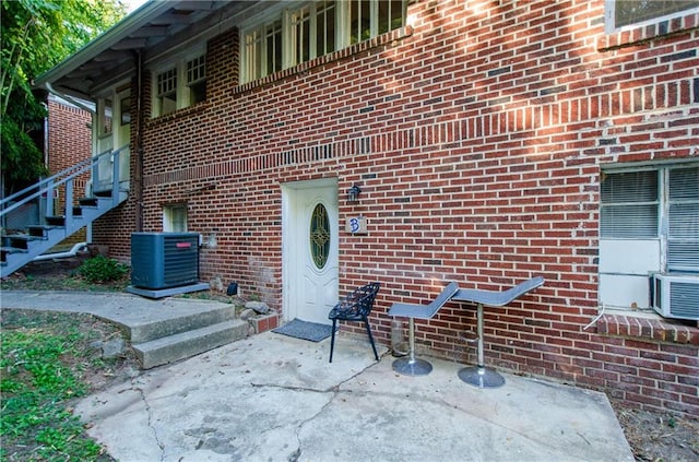 view of exterior entry featuring central air condition unit and a patio area