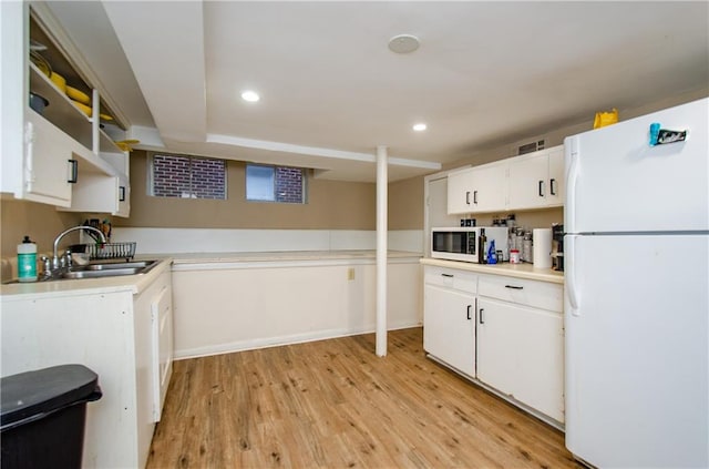 kitchen with sink, white cabinetry, light hardwood / wood-style flooring, and white appliances