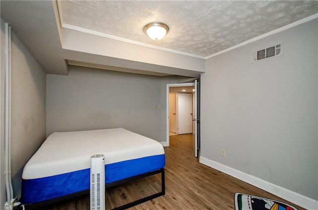 bedroom featuring hardwood / wood-style flooring, ornamental molding, and a textured ceiling