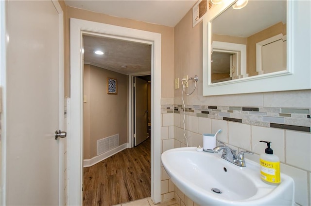 bathroom with hardwood / wood-style flooring, sink, and tile walls